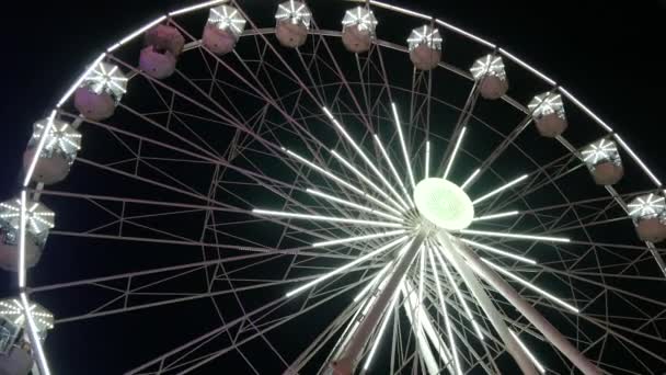 White big ferris wheel rotates against the background of the night sky. Ferris wheel with night illumination. lluminated Ferris Wheel construction — Vídeos de Stock
