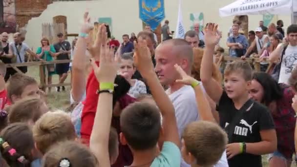 Trostyanets, Ukraina - 21 augusti 2021: En grupp barn leker, springer och skrattar intensivt med en vuxen presentatör på en festival för historisk återskapande — Stockvideo