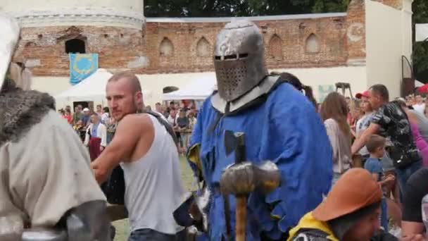 Trostyanets, Ucrania - 21 de agosto de 2021: Los espectadores miran con interés la reproducción de la batalla medieval. Las personas vestidas con armadura de caballero y cascos de metal y escudos luchan con acero frío — Vídeos de Stock