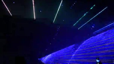 Gece gökyüzünün siyah arka planında hafif lazer gösterisi, açık hava gösterisi. Çok renkli lazer ışınları çeşitli şekillere dönüşür, dumandaki yansıma. Bilgi Teknolojisi Konferansı.