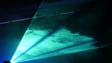 Gece gökyüzünün siyah arka planında hafif lazer gösterisi, açık hava gösterisi. Çok renkli lazer ışınları çeşitli şekillere dönüşür, dumandaki yansıma. Bilgi Teknolojisi Konferansı.