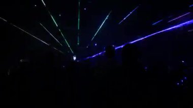 A modern laser light show, with a projection on smoke, a crowd of people watches the laser beams that turn into various lines and shapes. Outdoor performance