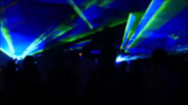 Modern bir lazer ışığı gösterisi, dumanla yansıtılan bir projeksiyonla, bir grup insan çeşitli çizgilere ve şekillere dönüşen lazer ışınlarını izliyor. Açık hava performansı