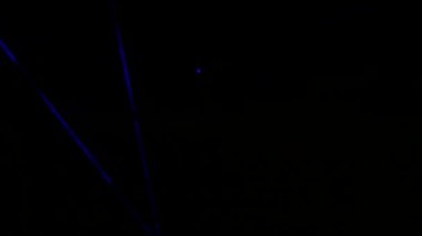 Gece gökyüzünün siyah arka planında hafif lazer gösterisi, açık hava gösterisi. Çok renkli lazer ışınları çeşitli şekillere dönüşür, dumandaki yansıma. Bilgi Teknolojisi Konferansı.