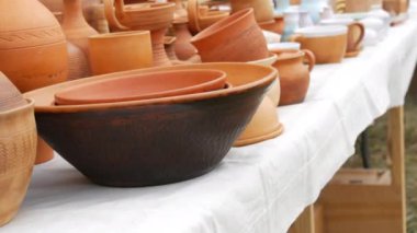 A variety of red clay utensils, ceramic pottery art on the outdoor counter. Street market exhibition of handmade pots, jars, ceramic products, souvenirs.