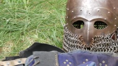 Medieval wrought iron armor and helmet lie on the grass at the festival of historical reenactment reconstruction