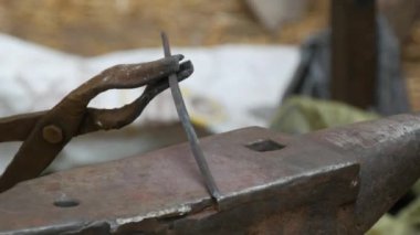 Medieval method of forging iron, the blacksmith forges an iron nail from the fire. Blacksmith is using hammer to forge metal