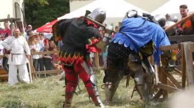 Trostyanets, Ukraine - August 21, 2021: Historical reconstruction of the medieval battle of knights in iron armor. Spectators crowd around the arena and watch the battle