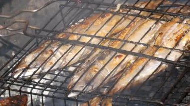 Grilled mackerel fish carcass with a slice of lemon. Grilled fish on a grill close-up view. Fish grill, street food festival, picnic in nature