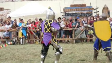 Trostyanets, Ukraine - August 21, 2021: Historical reconstruction of the medieval battle of knights in iron armor. Sword duel, battle with medieval weapons. Battle on ancient fortress