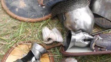 Medieval wrought iron armor and helmet lie on the grass at the festival of historical reenactment reconstruction