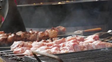 Büyük et parçaları ızgarada yatıyor ve kızartılıyor. Ateşin arka planında et yiyenler için nefis, doyurucu yemekler, yakın çekim manzarası..