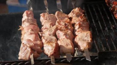 Büyük et parçaları ızgarada yatıyor ve kızartılıyor. Ateşin arka planında et yiyenler için nefis, doyurucu yemekler, yakın çekim manzarası..