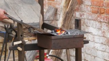 Medieval method of forging iron, the blacksmith forges an iron nail from the fire. Blacksmith is using hammer to forge metal