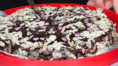 Sweet freshly baked homemade chocolate cake is cut with a knife into pieces close up view.