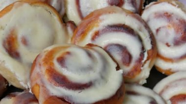 Round homemade baked cinnabons with white icing on top, close up view. Homemade buns