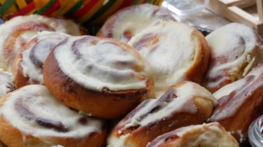 Round homemade baked cinnabons with white icing on top, close up view. Homemade buns