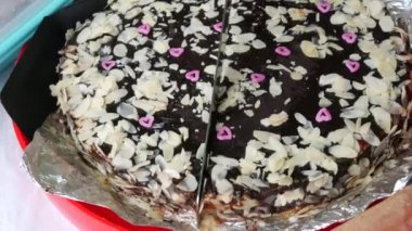 Sweet freshly baked homemade chocolate cake is cut with a knife into pieces close up view.
