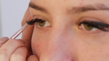 Woman professional make-up artist doing make-up of young girl model in beauty studio.