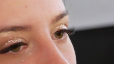 Woman professional make-up artist doing make-up of young girl model in beauty studio.