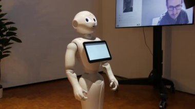Karlsruhe, Germany - August 13, 2022: Exhibition of modern robotics. Modern Robotic Technologies. White robot looks at camera and person. shows emotions. Raises his hands up, dances or is indignant.