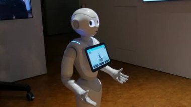 Karlsruhe, Germany - August 13, 2022: Exhibition of modern robotics. Modern Robotic Technologies. White robot looks at camera and person. shows emotions. Raises his hands up, dances or is indignant.