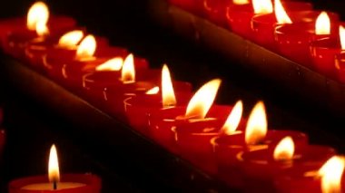 Row of lit burning red round candles in the cathedral. Religious candles for the rest of the soul in the catholic church.