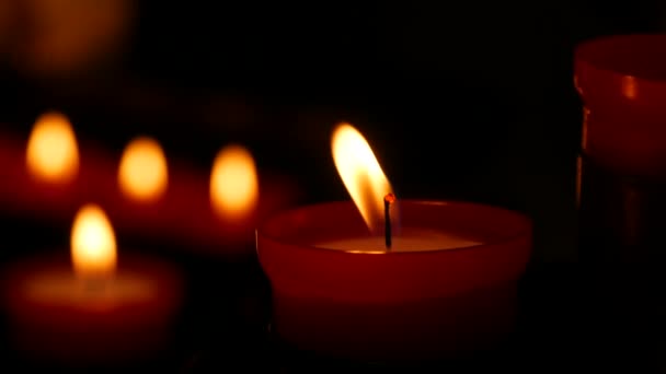 One flaming candle against a row of lit burning red round candles in a cathedral. Religious candles for the rest of the soul in the catholic church.