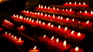 Row of lit burning red round candles in the cathedral. Religious candles for the rest of the soul in the catholic church.