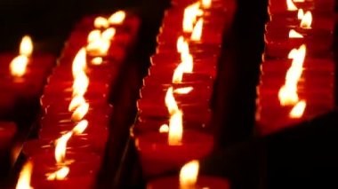 Row of lit burning red round candles in the cathedral. Religious candles for the rest of the soul in the catholic church.