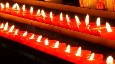 Row of lit burning red round candles in the cathedral. Religious candles for the rest of the soul in the catholic church.
