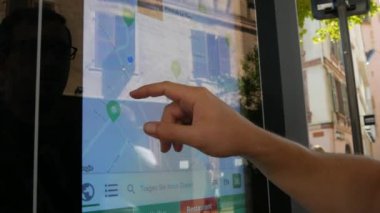 Colmar, France - August 7, 2022: A tourist is looking for information about attractions on digital screen in city. touch screen terminal in street. Big navigation outdoor on street. German Lettering.