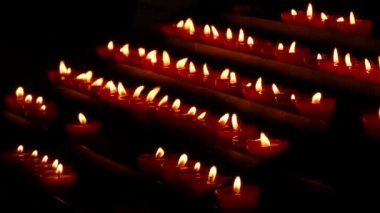Row of lit burning red round candles in the cathedral. Religious candles for the rest of the soul in the catholic church.