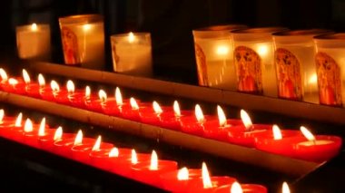 Row of lit burning red round candles in the cathedral. Religious candles for the rest of the soul in the catholic church.