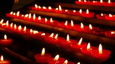 Row of lit burning red round candles in the cathedral. Religious candles for the rest of the soul in the catholic church.