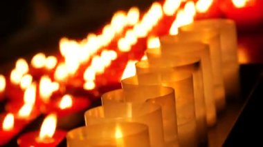 Row of lit burning red round candles in the cathedral. Religious candles for the rest of the soul in the catholic church.