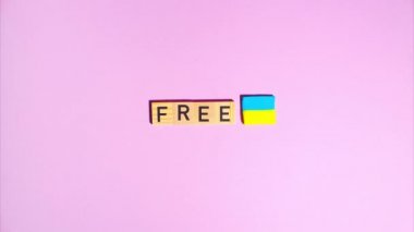 Plasticine stop motion animation. Wooden letters lay out the word free, plasticine Ukrainian flag appears and disappears on a purple background.
