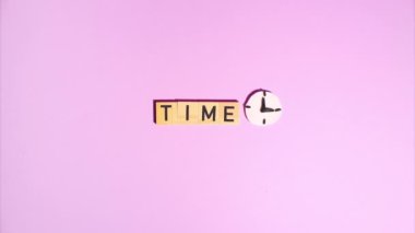 Plasticine stop motion animation. Wooden letters lay out the word time, a plasticine clock face appears and flickers against a purple background. Claymotion.