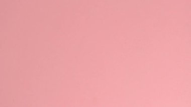 Stop motion animation. Red hearts and wooden letters that spell the word love on a pink background.