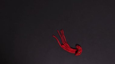 Plasticine stop motion animation or cartoon. Plasticine traditional Ukrainian motanka dolls, a red flower wreath and a white horned devil with red eyes appear on a black background.