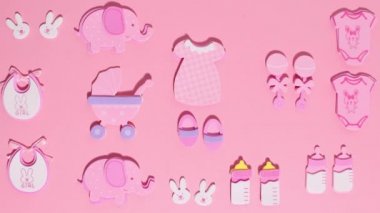 Funny pink stickers, symbolizing a newborn girl, appear on a pink background. Stop motion animation cartoon.