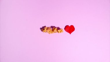 Plasticine stop motion animation. Wooden letters lay out the word love, a plasticine red heart appears and flickers on a purple background.