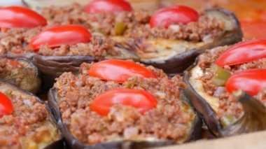 Greek or Turkish cuisine, eggplant stuffed with minced meat on top with tomato slices on the counter of the street food festival.