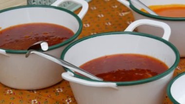 Freshly cooked asian red tomato soup next to spicy seasonings on the table.