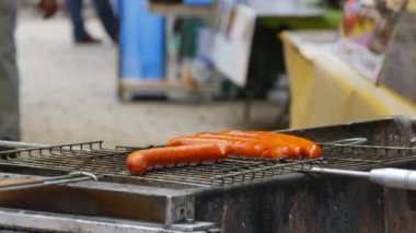 Four sausages on the grill outside. Fast food, street food festival. Grilled food fried and smoked in charcoal grills. Turns grill over with tasty delicious sausages. Concept for picnic and camping