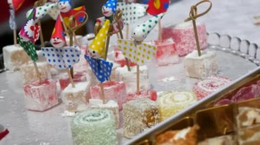 Turkish sweets Turkish delight on funny skewers clowns. The woman hand takes the sweetness from the tray.