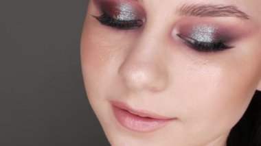 Şık makyajlı, dumanlı, poz veren ve gülümseyen güzel genç kız modeli, gri arka planda yüksek moda..