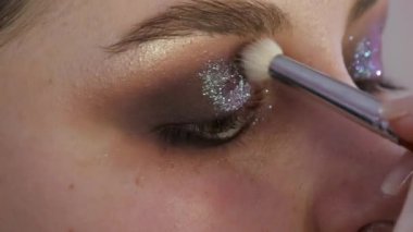 Model kızlar yakından bakar. Fırça göz kapağının altında gölge oluşturur..