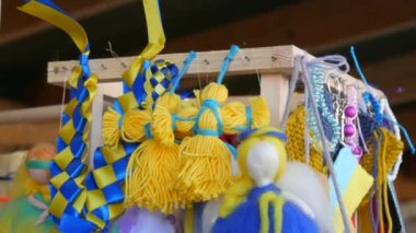 A womans hand hangs national Ukrainian motanka dolls in blue and yellow symbols of Ukraine at a fair in support of Ukraine.