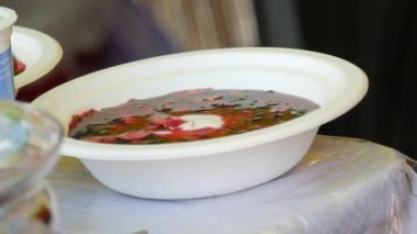 June 25, 2022 - Offenburg, Germany: Ukrainian national cuisine, borsch in which they put a spoonful of sour cream, a traditional dish on the counter of the fair in a disposable, plastic dish.